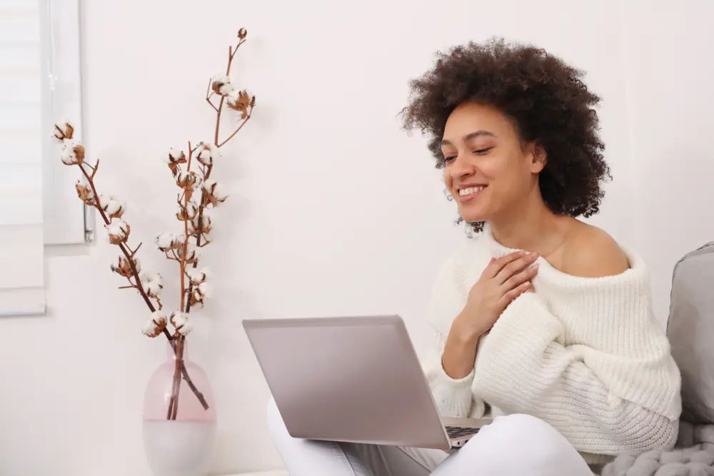 Smiling woman taking part in an online counselling session on her laptop at home.